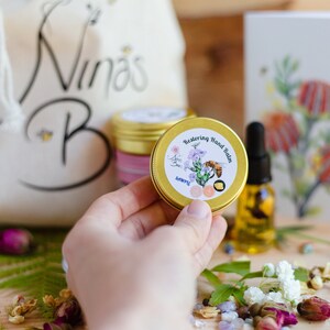 Nina's Bees Restoring Hand balm in a small container. it is a sample size 15 g product. Hand product for dry skin.  Experience the purity of nature with Nina’s Bees Restoring Hand Balm. Deep hydration in a waterless formula