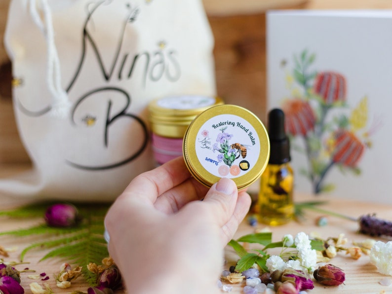 Nina's Bees Restoring Hand balm in a small container. it is a sample size 15 g product. Hand product for dry skin.  Experience the purity of nature with Nina’s Bees Restoring Hand Balm. Deep hydration in a waterless formula