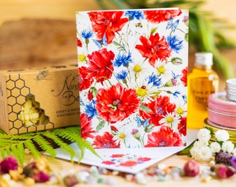 Könnte beinhalten: Eine florale Grußkarte mit weißem Hintergrund und roten Mohnblumen, blauen Kornblumen und weißen Gänseblümchen. Die Karte hat einen Aquarellstil und zeigt eine Biene und Schmetterlinge.