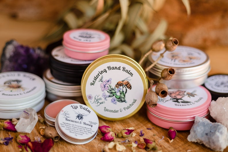 Ninas Bees Lip balm is next to other ninas bees balms. all balms are in colourful aluminium tins. It is a sustainable and environmentally friendly packaging for balms. Ninas bees balms have recycled paper labels