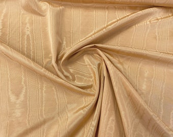 Puede incluir: Primer plano de una tela plegada y brillante en un tono beige dorado cálido. El material tiene un sutil patrón de rayas verticales, creando una apariencia texturizada. Los pliegues y drapeados de la tela añaden profundidad y dimensión a la imagen.
