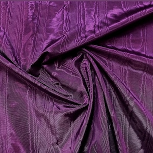 Könnte beinhalten: Nahaufnahme eines tiefvioletten Stoffes mit vertikalem, strukturiertem Muster. Der Stoff hat eine glänzende, fast irisierende Qualität, wobei Falten und Schatten Tiefe verleihen. Das Material scheint ein luxuriöses Textil zu sein, möglicherweise geeignet für Kleidung oder Heimdekoration.