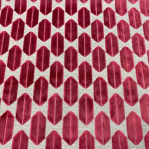 May include: A close-up of a fabric with a repeating pattern of burgundy-colored hexagons on a light gray background.