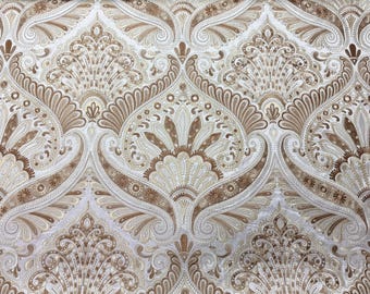 May include: A fabric featuring a repeating damask pattern in shades of metallic gold, bronze, and cream. The design consists of intricate, symmetrical floral and paisley-inspired motifs with swirling lines and small circular accents throughout.