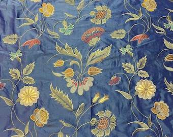 May include: Blue fabric with a repeating pattern of gold and red embroidered flowers. The fabric has a subtle sheen and a soft texture.