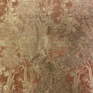 May include: A close-up of a fabric with a repeating pattern of trees, water, and foliage. The fabric is a reddish-brown color with gold accents.