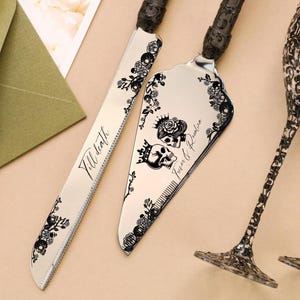Könnte beinhalten: Ein Kuchenmesser- und Servier-Set mit schwarzen Blumen- und Totenkopfmotiven. Auf dem Messer steht "Till death" und auf dem Servierer "Forever & Always". Die Griffe sind schwarz und strukturiert.