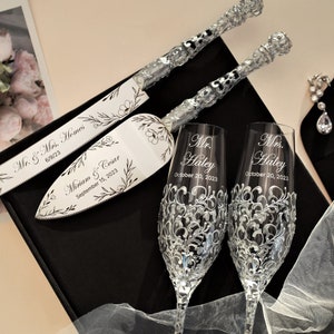 May include: A wedding cake cutting set with two champagne flutes. The cake knife and server are engraved with the names "Miriam & Criar" and the date "September 15, 2023". The champagne flutes are engraved with "Mr. Haley" and "Mrs. Haley" and the date "October 20, 2023".