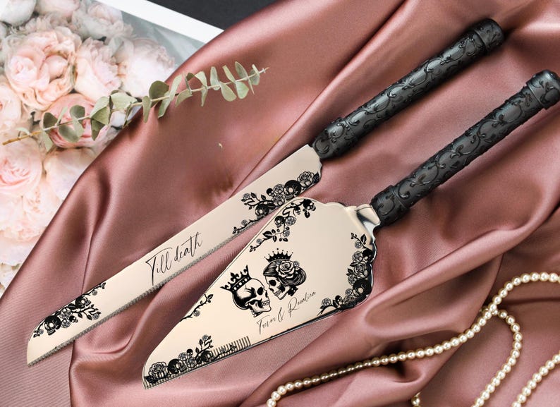 May include: A cake knife and server set with black floral and skull designs. The knife has the text "Till death" and the server has the text "Forever & Rosaline". The handles are black with a decorative pattern.
