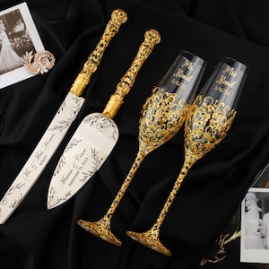 May include: Gold wedding cake knife and server set with a floral design and the text "Mr. & Mrs. (names) September 18, 2023". Two gold-rimmed champagne flutes with the text "Mr. Bond 5/6/23" and "Mrs. Bond 5/6/23".