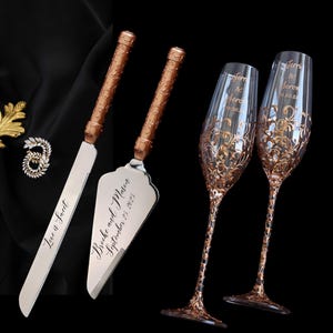 May include: A wedding cake knife and server set with engraved text, "Love is Sweet" and "Brooke and Mason September 23, 2023". Two champagne flutes with gold filigree and engraved names and date. The set is displayed on a black background.