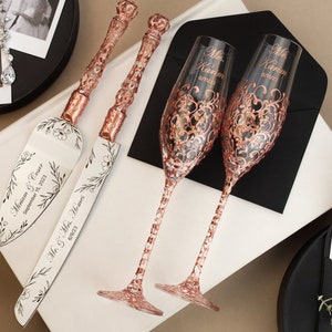 May include: Rose gold wedding cake knife and server set with floral design and the text "Miriam & Kevin September 15, 2023" and "Mr. & Mrs. Hemmer 2023". Two rose gold champagne flutes with a floral design and the text "Mr. Kevin" and "Mrs. Kevin" on each.