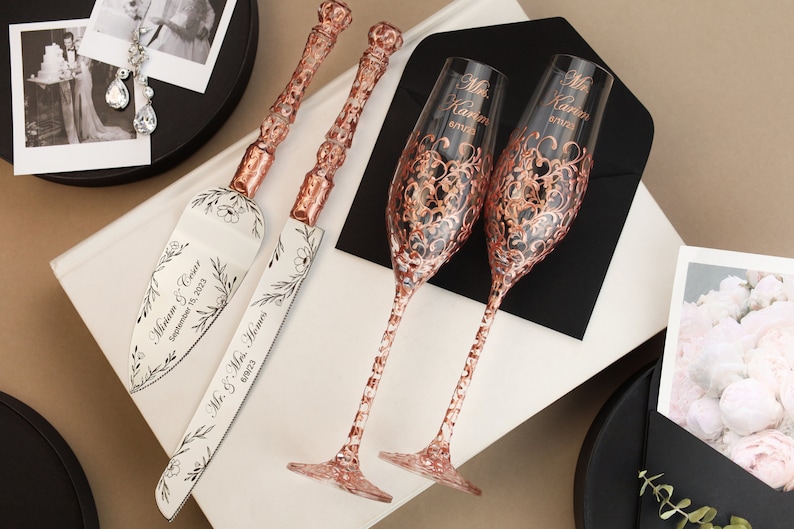May include: Rose gold wedding cake knife and server set with floral design and the text "Miriam & Kevin September 15, 2023" and "Mr. & Mrs. Hemmer 2023". Two rose gold champagne flutes with a floral design and the text "Mr. Kevin" and "Mrs. Kevin" on each.