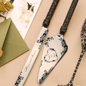 May include: Silver cake knife and server set with black floral and skull accents. The knife is engraved with "Always and Forever". The server features a heart design with initials. The handles are black.