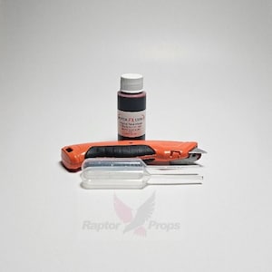 May include: A small bottle of red liquid labeled "Raptor FX SFX" Original Fake Blood. The bottle is next to a clear plastic dropper and an orange utility knife.