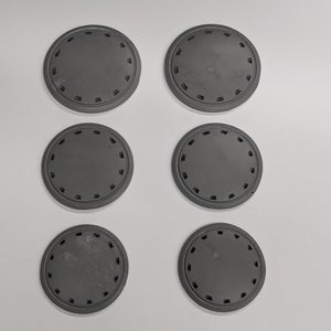 Puede incluir: Seis posavasos redondos de pl&aacute;stico gris con un patr&oacute;n decorativo alrededor del borde.