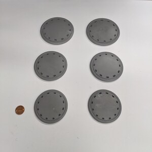 Puede incluir: Seis posavasos redondos decorativos grises con un dise&ntilde;o circular elevado alrededor del borde.