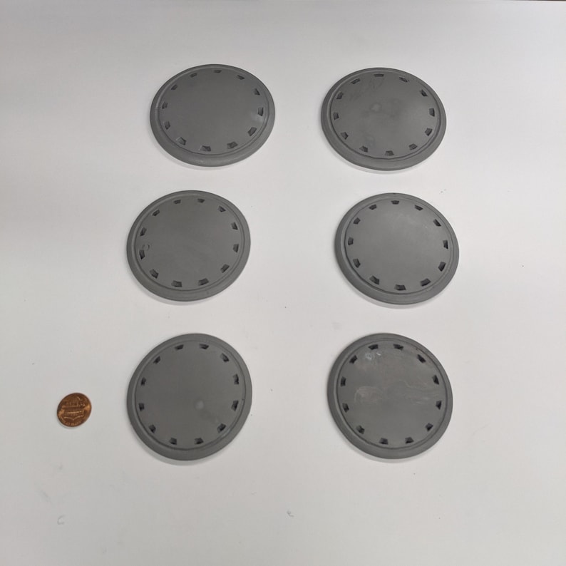 Puede incluir: Seis posavasos redondos decorativos grises con un dise&ntilde;o circular elevado alrededor del borde.