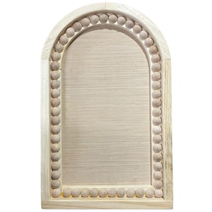 May include: A light-colored wooden arched mirror with a beaded border. The frame is rectangular with a rounded top, and the interior is a light, neutral color. The mirror is a decorative item.