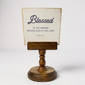 Rustic wooden pedestal display stand with a small metal clip holding a blank card for photo display, note, or wedding table number.
