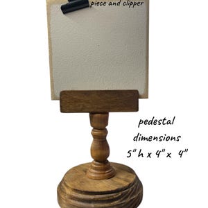 Rustic wooden pedestal display stand with a small metal clip holding a blank card for photo display, note, or wedding table number.