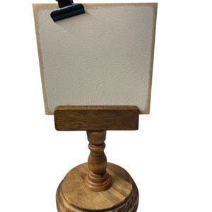 Rustic wooden pedestal display stand with a small metal clip holding a blank card for photo display, note, or wedding table number.