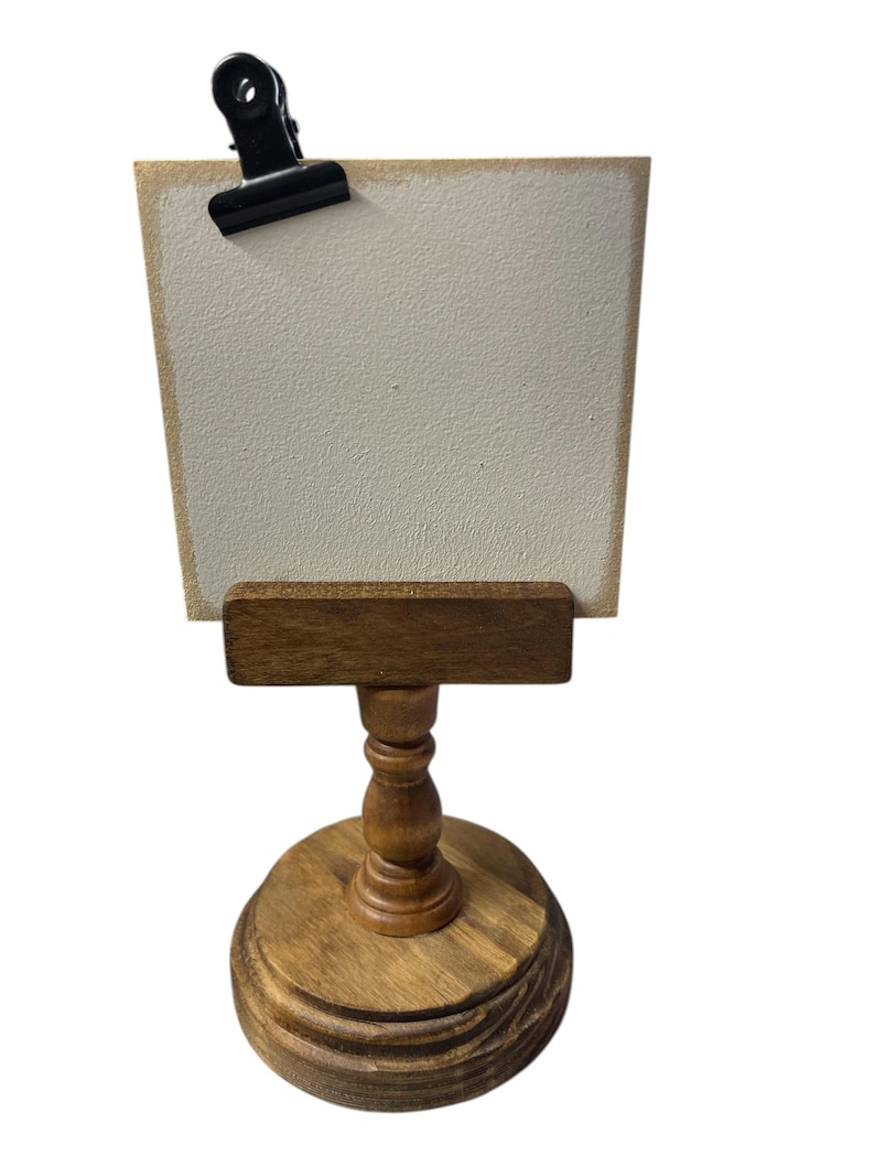 Rustic wooden pedestal display stand with a small metal clip holding a blank card for photo display, note, or wedding table number.