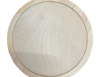 Puede incluir: Un posavasos redondo de madera sin terminar con un centro empotrado. El posavasos está hecho de madera de color claro y tiene un patrón de vetas natural. El borde exterior está ligeramente elevado, creando un borde definido.
