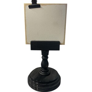 Rustic wooden pedestal display stand with a small metal clip holding a blank card for photo display, note, or wedding table number.