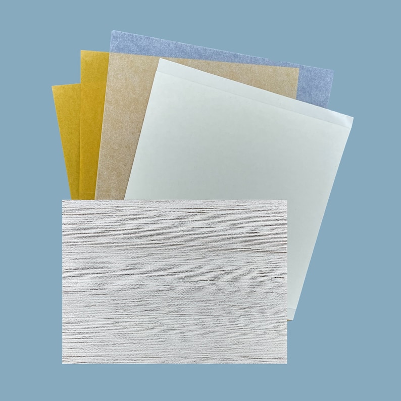 May include: A stack of different colored paper sheets, including blue, brown, and gold, on top of a white textured surface.