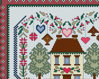 Puede incluir: Un diseño de punto de cruz que presenta una casa con techo marrón, rodeada de árboles y una valla, todo dentro de un borde en forma de corazón. El diseño incluye el texto "LOVE LIVES HERE" y varios motivos de corazón. El borde es una mezcla de rojo, verde y blanco.
