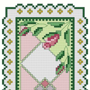 Puede incluir: Una alfombra rectangular blanca y rosa con un borde verde y un diseño floral en las esquinas. La alfombra tiene un patrón de diamante en el centro.