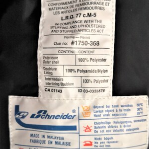 Puede incluir: Etiqueta blanca con texto negro que detalla la composici&oacute;n del material de una chaqueta. La etiqueta dice "Material Neuf Seulement" y "New Material Only". La etiqueta tambi&eacute;n incluye instrucciones de cuidado para lavar, secar y planchar la chaqueta. La etiqueta est&aacute; unida a una chaqueta negra.