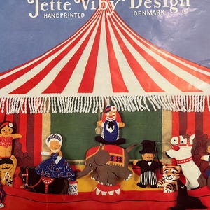 May include: A set of felt circus characters, including a clown, an elephant, a horse, a tiger, a ringmaster, a lady in a dress, a girl in a swimsuit, and a boy with a mustache. The characters are arranged in front of a red and white striped circus tent.