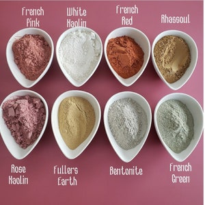May include: Eight small white bowls filled with different types of clay powders, including French Pink, White Kaolin, French Red, Rhassoul, Rose Kaolin, Fullers Earth, Bentonite, and French Green.