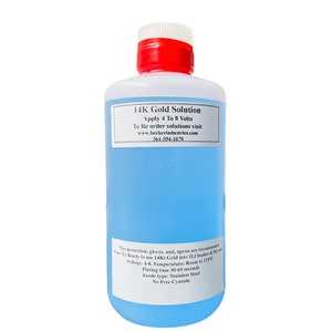 Puede incluir: Una botella de plástico transparente con tapa roja y etiqueta blanca que contiene un líquido azul. La etiqueta dice "14K Gold Solution" y proporciona instrucciones de uso. La botella está diseñada para aplicar oro.