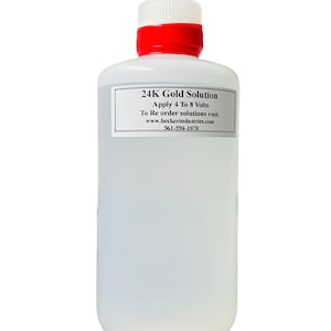 May include: A clear plastic bottle with a red lid containing 24K gold solution. The label reads "24K Gold Solution Apply 4 To 8 Volts To Re order solutions visit www.beckerindustries.com 561-594-1070".