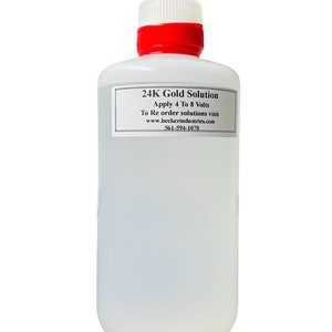 Puede incluir: Una botella de plástico transparente con tapa roja que contiene solución de oro de 24 quilates. La etiqueta dice "24K Gold Solution Apply 4 To 8 Volts To Re order solutions visit www.beckerindustries.com 561-594-1070".