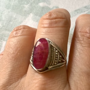 Op de afbeelding: Een zilveren ring met een roze ovale edelsteen gezet in een filigraan ontwerp.