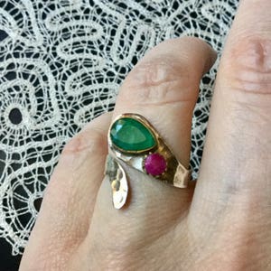 Peut inclure: Une bague en argent avec une pierre précieuse verte et une pierre précieuse rose. La bague est conçue dans une forme organique unique.