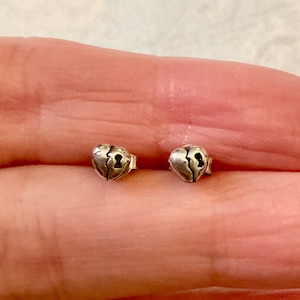 Peut inclure: Une paire de boucles d'oreilles clous en forme de cœur argentées. Chaque boucle d'oreille présente un cœur brisé avec un détail de trou de serrure. Les boucles d'oreilles sont petites et délicates.