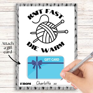 May include: A white card with black text that reads "Knit Fast Die Warm" with a black and white illustration of a ball of yarn and knitting needles. The card has a blue gift card with a blue bow and the text "Gift Card" on it. The card also has the text "From" and a space for a name.