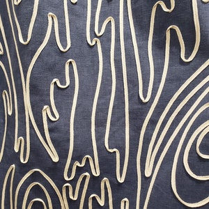 May include: A dark blue fabric with a white embroidered pattern of abstract shapes and lines.