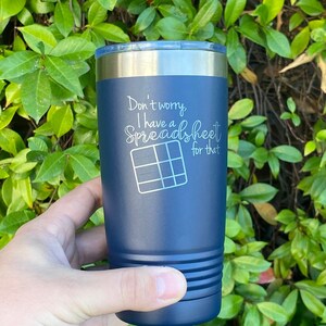 May include: A dark blue stainless steel tumbler with a white inscription that reads "Don't worry, I have a spreadsheet for that".