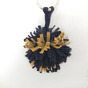 May include: A black and gold pom-pom keychain with a silver key ring.