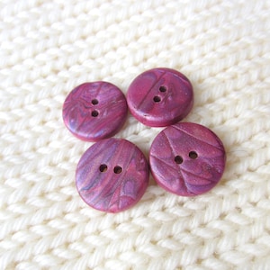 May include: Four round, pink and purple swirl buttons with two holes each.