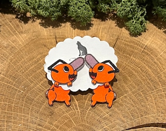 May include: A pair of orange and black cartoon bunny rabbit earrings with a white background. The earrings are on a white card with a black cat silhouette.