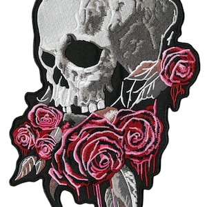 Pode incluir: Patch bordado com uma caveira detalhada em cinza e branco. A caveira é adornada com vibrantes rosas vermelhas e folhas, sobre um fundo preto. O patch tem um tema gótico ou motociclista.