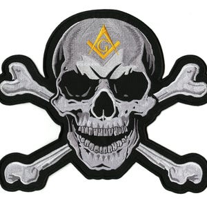 Könnte beinhalten: Gestickter Aufnäher mit einem Totenkopf mit gekreuzten Knochen. Der Totenkopf ist grau und weiß mit schwarzen Augenhöhlen und einem grinsenden Mund. Ein gelbes Freimaurersymbol befindet sich auf der Stirn. Der Aufnäher hat einen schwarzen Rand.