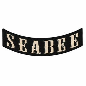 May include: Black, curved patch with the word "SEABEE" embroidered in off-white, bold, serif font. The patch has a black border and a white background. The patch is likely for a jacket or vest.